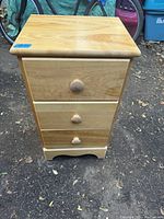 Front view of solid wood 3 drawer end table showing wood grain and drawer knobs.