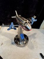 Front view of polished stainless steel airplane light with two blue propellers and a curved mounting base.