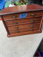 Front view of the oak jewellery box showing four drawers with decorative handles