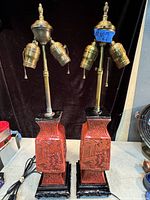 Full view of a pair of antique cinnabar Asian lamps showing carved rectangular bases with brass necks and dual light sockets with pull chains.