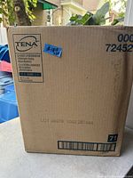 Photo showing the front side of a sealed cardboard box labeled TENA Unisex Underwear size XL, quantity of 48 pieces, ultimate-extra absorbency specification.