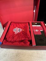 Photo of folded red Toronto FC scarf inside a red box with authenticity card and tags visible.