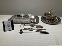 Full view of all items showing two dessert bowls, trays, sugar bowls, tongs, server, and candle snuffer.