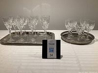 Full view of both sets of wine glasses on metal serving trays, eight white wine glasses on left tray and five red wine glasses on right tray.