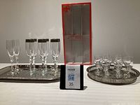Overall view of all glassware items displayed on metal trays with box behind