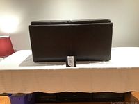 Side view of dark brown leather storage bench showing rectangular shape and cushioned top with divided sections.