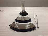 Overview of three Swarovski crystal swan figurines, glass vase and elephant pendant necklace on mirrored half-round stands