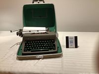 Vintage Royal typewriter placed inside the open green hard carrying case on a table, showing full view of the machine and case.