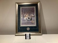 Full view of framed artwork titled Ice Dancer showing winter scene with family and dog ice skating.