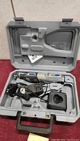 Dremel 8220 rotary tool kit in open molding carrying case showing tool, charger, handle attachment, and power adapter.
