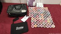 Photo showing 86 small round Scentsy wax sample containers arranged in rows alongside two black Scentsy branded carrying cases and white felt shapes.