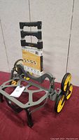 Overall view of the All Terrain UpCart stair climber cart showing gray frame, foldable platform, and large yellow tri-wheels designed for climbing stairs.