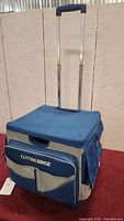 Blue and beige Cutting Edge craft cart with extendable handle and front pocket.