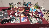 Overview of various Halloween accessories displayed on a table including headbands with ears, glasses, masks, and feathered pieces.