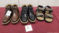 Three pairs of men's shoes on display: two pairs of boots (brown and black) new with tags and one pair of sandals lightly used, all size 11.