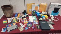 Full view of various office supplies including markers, envelopes, scissors, pins, tape, desk organizer, and more arranged on a table