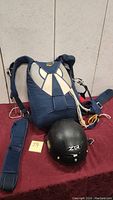 Full view of blue Wings parachute harness and black ZR helmet on table