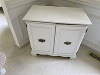 Closed white wooden cabinet with decorative brass handles on doors.