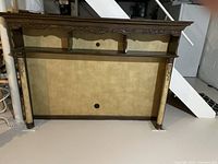 Front view of decorative fruitwood TV hutch with shelf, carved details on top trim and side columns, cable management holes in back panel