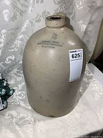 Front view of the stoneware jug showing overall shape and finish, including the label stamped on the front.