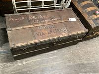 Photo of the antique wooden military trunk showing top surface with handwritten and stenciled markings.