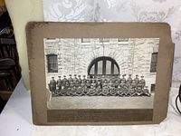 Full view of mounted antique black and white group military photo, including the mounting board with typed label and edge wear visible.