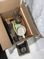 Box containing vintage straight razors, after shave bottles, shaving mug, brush, and stropper box.