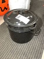 Photo of the assembled large black enamel canning pot with lid on, showing speckled enamel finish and handles on the side.