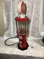 Overall front view of red metal and plastic vintage gas pump model with Esso branding and illuminated top globe showing 'Imperial'