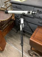 Side view of the Bushnell telescope mounted on a tripod. Shows the full optical tube, tripod legs, and part of the accessory tray.
