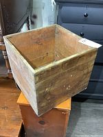 Angled view showing exterior wood panels and markings on the butter box including faded text and paint spots.