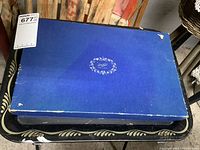 Blue box with oval floral logo showing wear on edges and corners