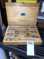 Open pine case showing all seven chisels in fitted slots