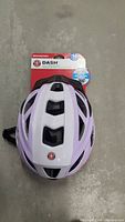 Top view of Schwinn Dash adult bike helmet, white with purple accents, showing ventilation slots and attached packaging label.