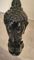 Front view showing facial features and base of black ceramic Buddha head sculpture
