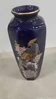 Hexagonal cobalt blue Japanese porcelain vase with peacock and flower design, gold rim detail.