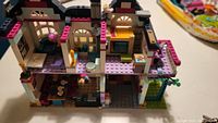 Two-story LEGO house showing interior rooms with purple, pink, and yellow bricks