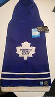 Front side of the blue knit Toronto Maple Leafs dog sweater showing logo patch and tags.