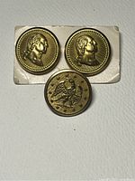 Front view of two brass George Washington portrait buttons and one navy coat button with eagle and stars motif.