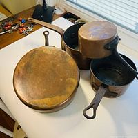 Overall view of four copper pans and saucepans on white background