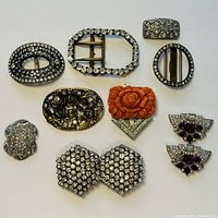 Front view of 11 assorted vintage metal buckles and clips featuring rhinestones, floral motifs, and carved coral rose detailing.
