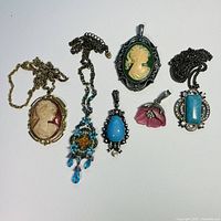 Photo showing all six pendants with various colors and styles including cameos, floral, turquoise, and beaded designs