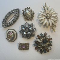 Overview of 7 vintage pins showing various designs including floral, geometric, rhinestones, faux pearls and enamel details.