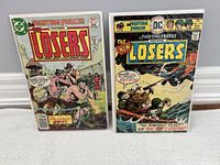 Photo of two The Losers comic books from 1977, both in protective bags and boards.