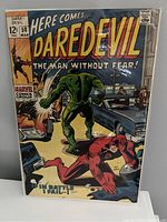 Comic book Daredevil #50 from 1969 with cover showing Daredevil in red and a green monster near cars, bagged and boarded.