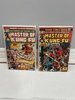 Photo of two Master of Kung Fu comics standing side by side showing the front covers, bagged and boarded.