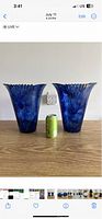 Two blue Murano glass vases with ruffled edges and a can for size reference on a wooden table.