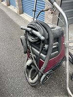 Side view of machine showing hoses coiled on top, wheels and base