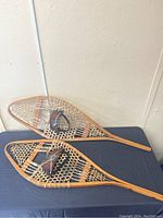 Pair of antique wooden snowshoes laid flat on a table, showing overall shape and condition.