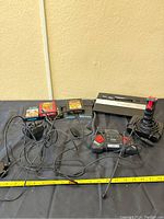 Atari 2600 console with two controllers and six game cartridges laid out on a black surface with cords